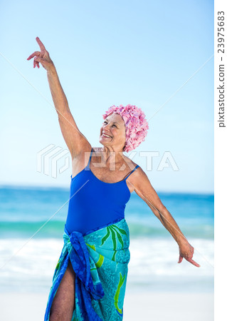 Pretty mature woman raising her arms on the beach Pretty mature woman raising her arms on the beach 23975683