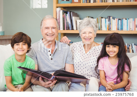 Portrait of grandparents showing album to grandchildren Portrait of grandparents showing album to grandchildren 23975768