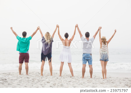 Rear view of friends holding hands and standing in a row 23975797