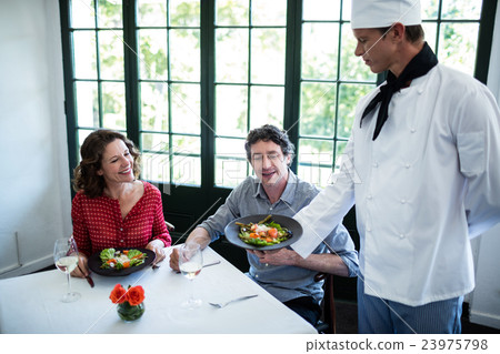 Chef showing the meal plate to couple Chef showing the meal plate to couple 23975798