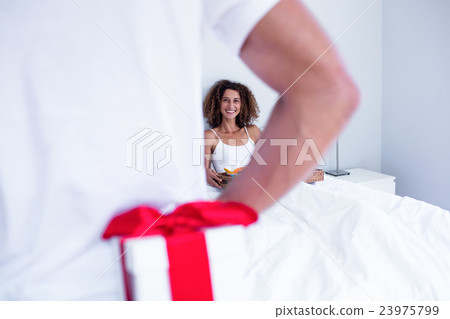 Man hiding gift behind his back for wife Man hiding gift behind his back for wife 23975799