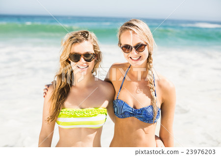 Portrait of two happy women in bikini standing on the beach Portrait of two happy women in bikini standing on the beach 23976203