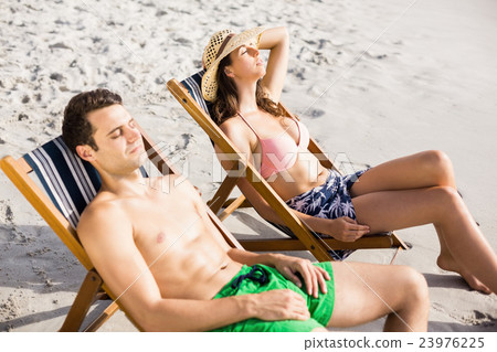 Young couple relaxing on armchair on the beach 23976225