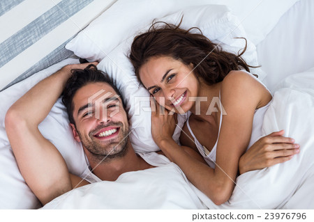 High angle portrait of cheerful couple relaxing on bed High angle portrait of cheerful couple relaxing on bed 23976796