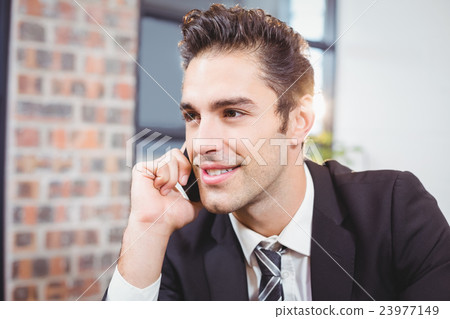 Businessman talking on mobile phone in office 23977149
