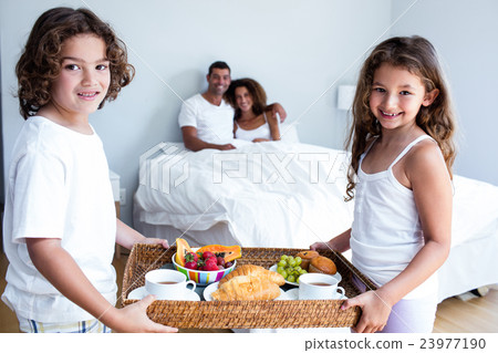 Portrait of daughter and son carrying breakfast tray for parents Portrait of daughter and son carrying breakfast tray for parents 23977190