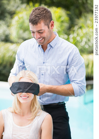 Smiling man blindfolding woman Smiling man blindfolding woman 23977192