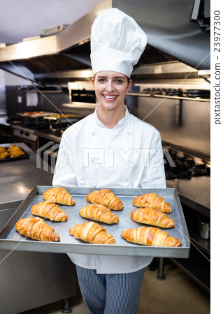 Portrait of a chef holding tray of croissants 23977300