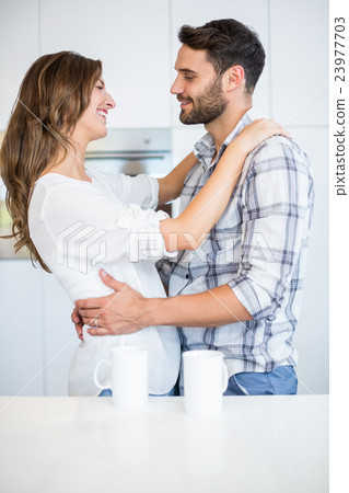 Couple embracing by table at home 23977703