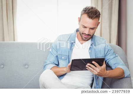 Young man using digital tablet on sofa Young man using digital tablet on sofa 23977939
