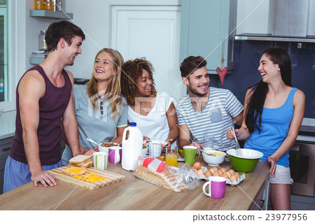 Smiling friends discussing at breakfast table 23977956