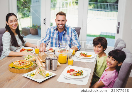 Portrait of smiling family sitting at dining table 23977958