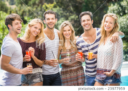 Portrait of friends having juice near pool 23977959