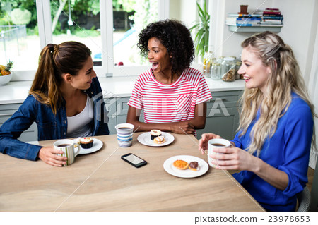 Female friends laughing while having breakfast Female friends laughing while having breakfast 23978653