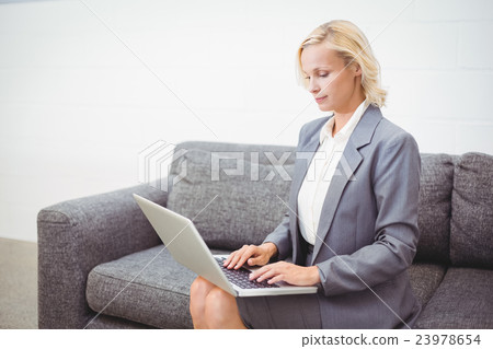 Bussinesswoman working on laptop while sitting on sofa 23978654