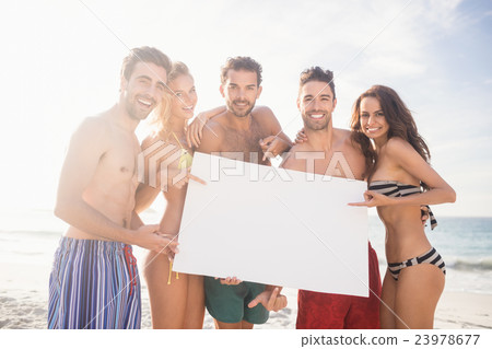 Happy friends in swimwear holding a sign 23978677