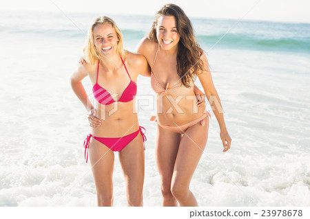 Portrait of two happy women in bikini standing on the beach Portrait of two happy women in bikini standing on the beach 23978678