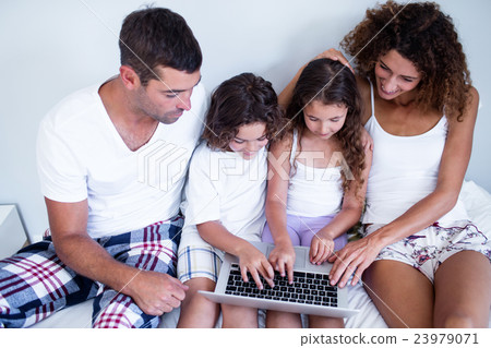 Family using laptop together on bed Family using laptop together on bed 23979071