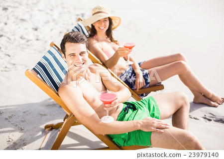 Portrait of young couple sitting on armchair with cocktail drink 23979140