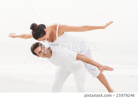 Man giving a piggy back to woman on the beach 23979246