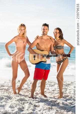 Happy friends posing and playing guitar on the beach Happy friends posing and playing guitar on the beach 23979638