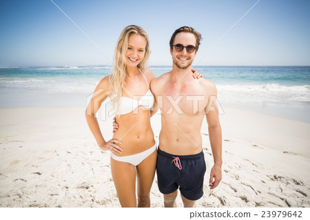 Portrait of young couple standing on the beach 23979642