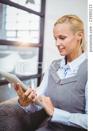 Businesswoman using tablet while sitting on sofa Businesswoman using tablet while sitting on sofa 23980215