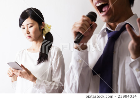 A man who sings at karaoke and a woman who operates a cell phone 23994014