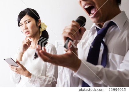 A man who sings at karaoke and a woman who operates a cell phone 23994015