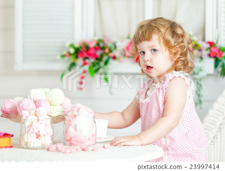 Little cute curly girl  eating different sweets. 23997414