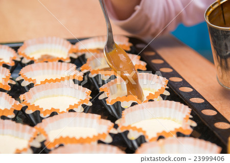 Boiled condensed milk is added as a filling into molds of muffins 23999406