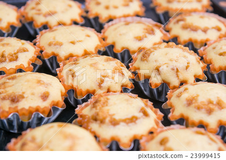 Freshly baked muffins in metal tins 23999415
