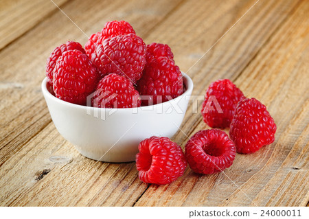 Raspberry in bowl on wooden table 24000011