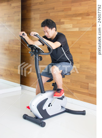 Asian Man On Excercise Bike At Fitness Center. Asian Man On Excercise Bike At Fitness Center. 24007792