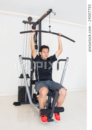 Asian Man Doing Exercise On Fitness Machine In Gym Asian Man Doing Exercise On Fitness Machine In Gym 24007793