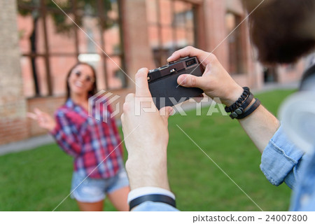 Guy photographing his girlfriend outdoors Guy photographing his girlfriend outdoors 24007800