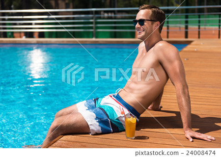 Pleasant cheerful man sitting near swimming pool Pleasant cheerful man sitting near swimming pool 24008474