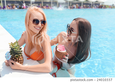 Happy young women drinking cocktails in pool 24010337