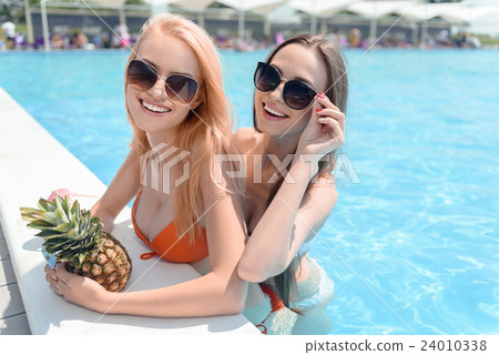 Carefree ladies having fun in pool 24010338