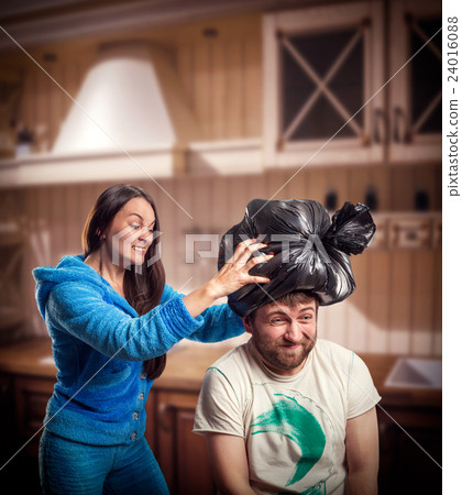 Wife putting trash pack on her husband head Wife putting trash pack on her husband head 24016088