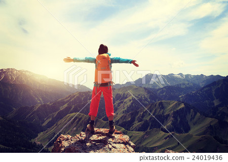 cheering young woman backpacker open arms on mountain peak cliff 24019436
