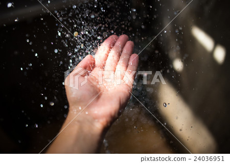 Human hand in sunlight under falling water. 24036951