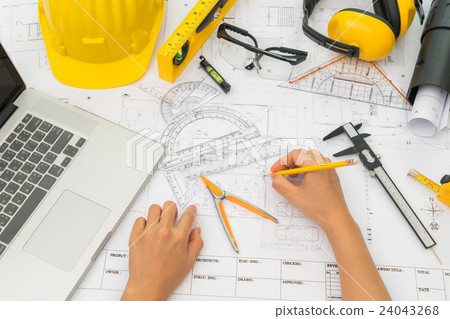 Hand over Construction plans with yellow helmet and drawing tools on blueprints . Hand over Construction plans with yellow helmet and drawing tools on blueprints . 24043268