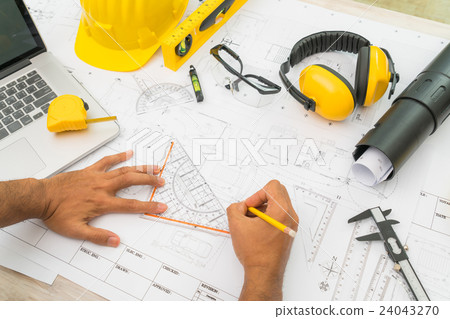 Hand over Construction plans with yellow helmet and drawing tools on blueprints . Hand over Construction plans with yellow helmet and drawing tools on blueprints . 24043270