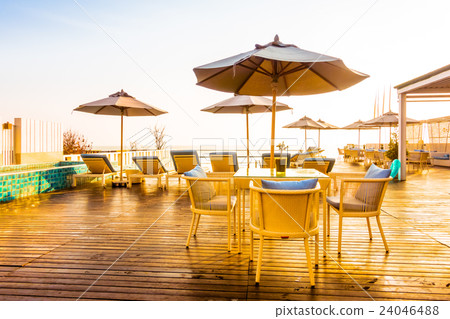 Umbrella and chair around swimming pool 24046488