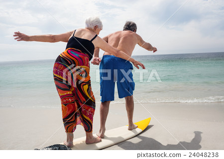 Senior couple surfing on beach Senior couple surfing on beach 24048238