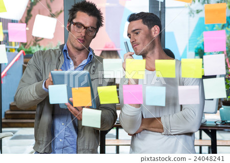 Colleagues looking at sticky notes and tablet Colleagues looking at sticky notes and tablet 24048241