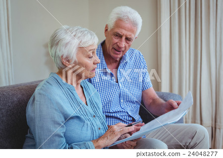 Senior couple with bills while sitting on sofa  24048277