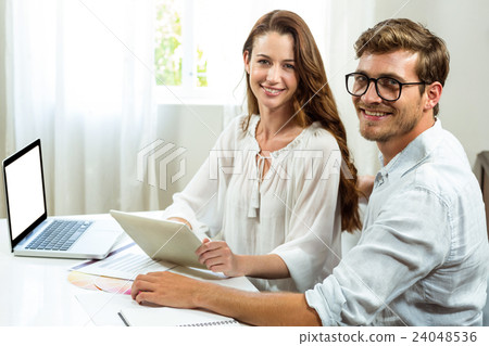 Portrait of male and female colleagues discussing document at office Portrait of male and female colleagues discussing document at office 24048536