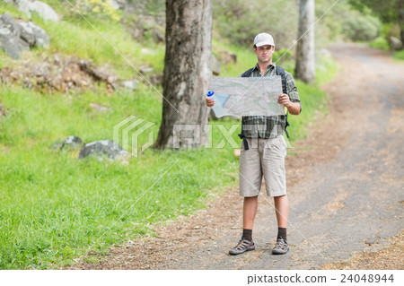 Young man reading map on footpath in forest 24048944